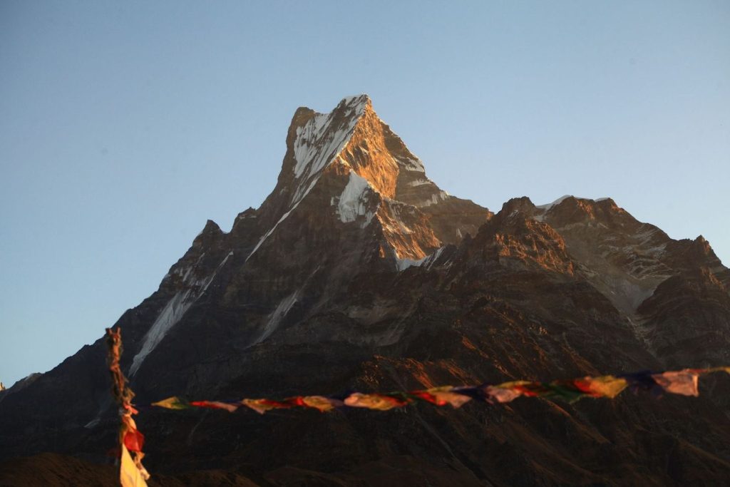 Panoramic view of Mardi Himal Base Camp in Nepal with snow-capped peaks, lush green forests, and trekking trail in the foreground.