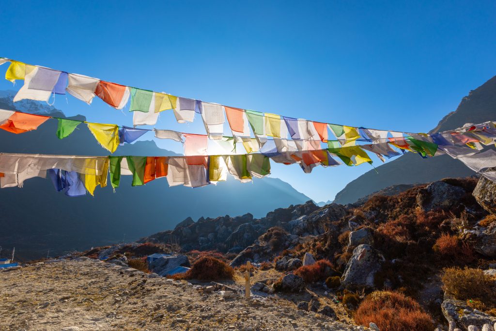 Vibrant prayer flags under blue sky in the serene Langtang Valley, Nepal.