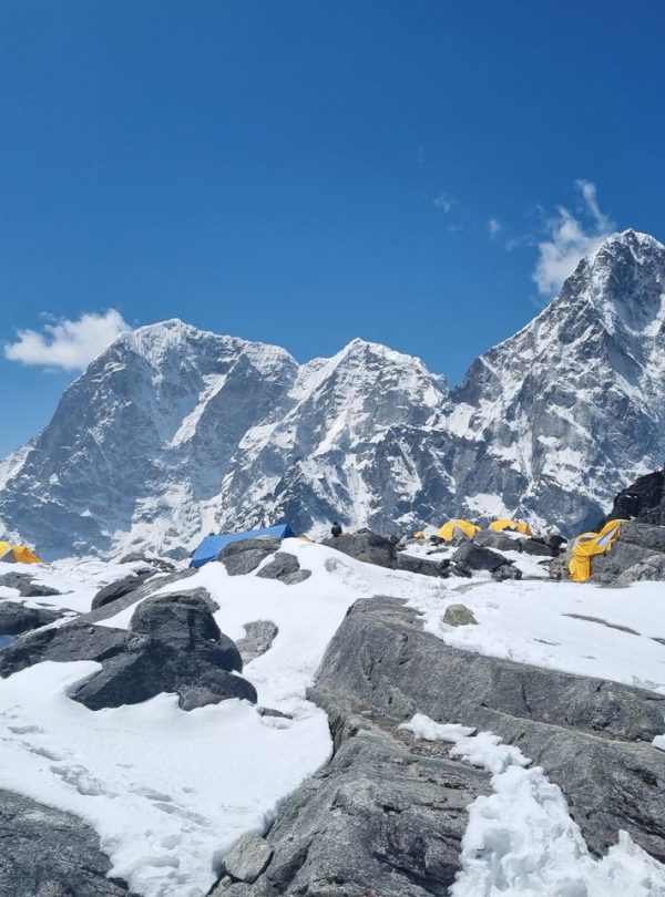 Snow-covered Himalayan peaks and colorful prayer flags at a base camp in Khumjung, Nepal.
