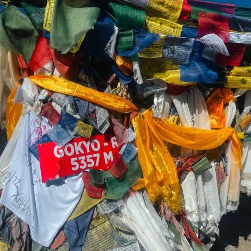 Vibrant prayer flags at Gokyo-Ri summit, Nepal, showcasing spirituality and culture at 5357 meters elevation.