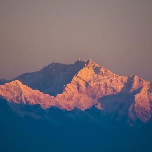 Stunning sunrise view of Kanchenjunga, the third highest mountain, bathed in warm light.