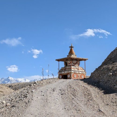 Colorful stupa on a rocky path in the Himalayas with a clear blue sky.