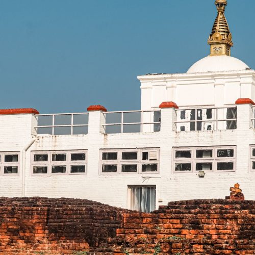 Lumbini site showcasing ancient brick ruins beneath a modern structure under clear blue skies.