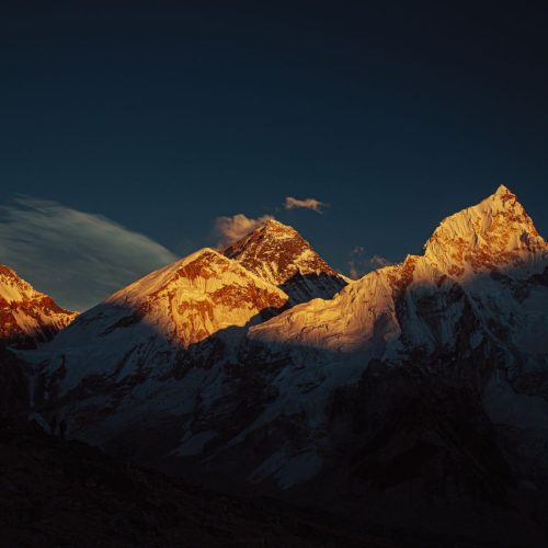 Spectacular view of Mount Everest and surrounding peaks at sunset with golden-lit summits.
