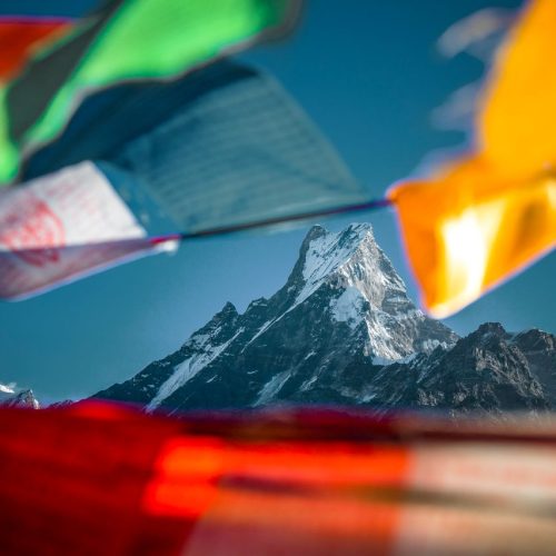 Majestic mountain peak surrounded by vibrant prayer flags in the Himalayas, Nepal.