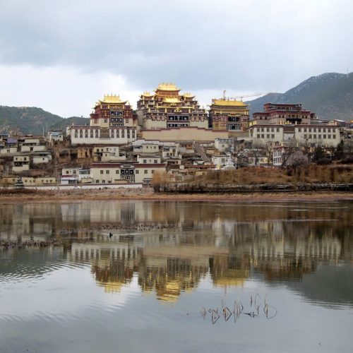 Picturesque view of Ganden Sumtseling Monastery reflecting on the lake in Yunnan, China.