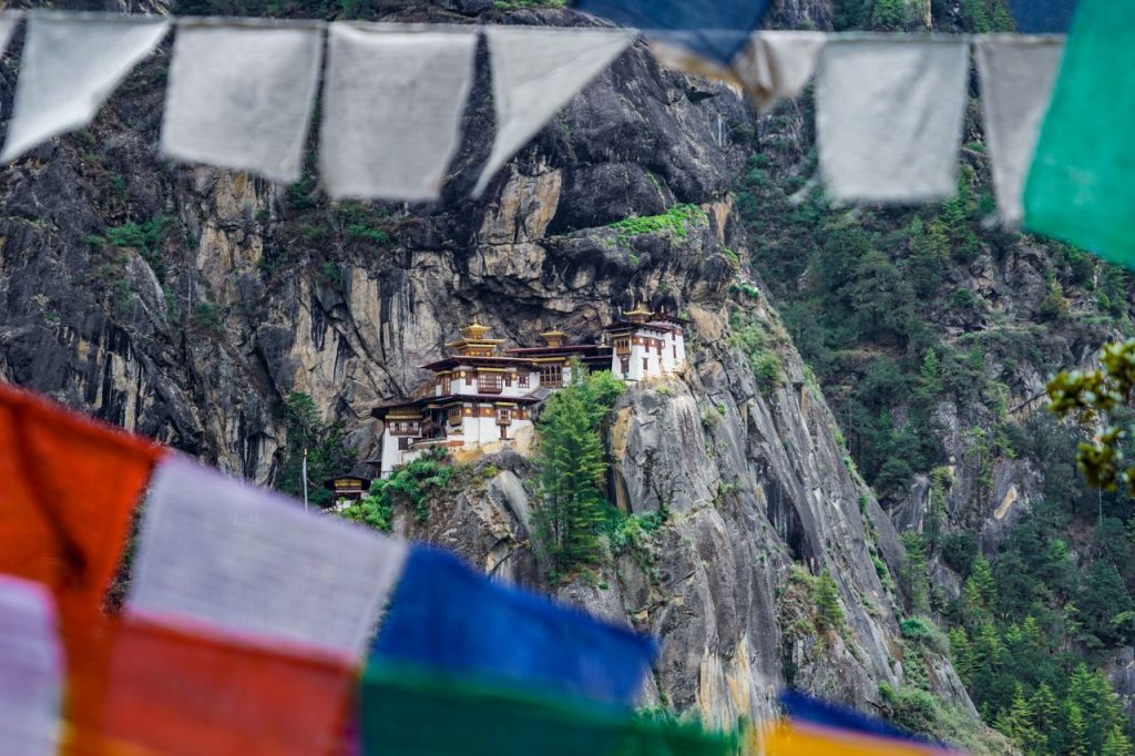 A stunning view of Paro Taktsang Monastery nestled in the cliffs of Bhutan with vibrant prayer flags.
