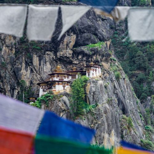 A stunning view of Paro Taktsang Monastery nestled in the cliffs of Bhutan with vibrant prayer flags.