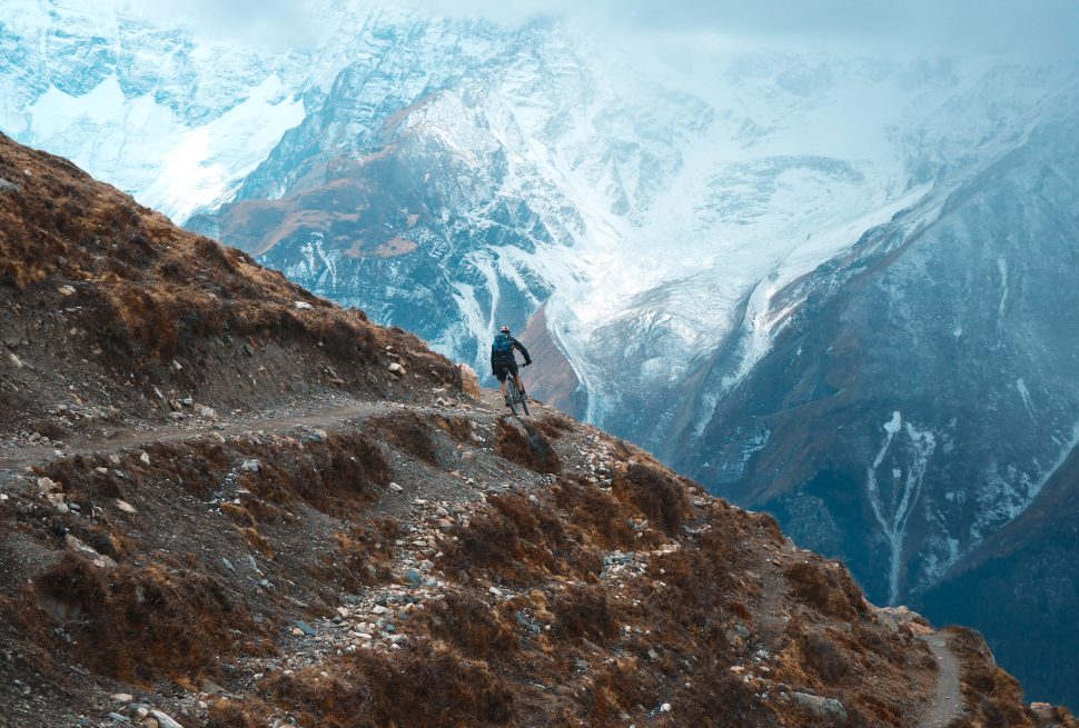 Mountain biker riding singletrack through pine forest above Kathmandu Valley, Nepal